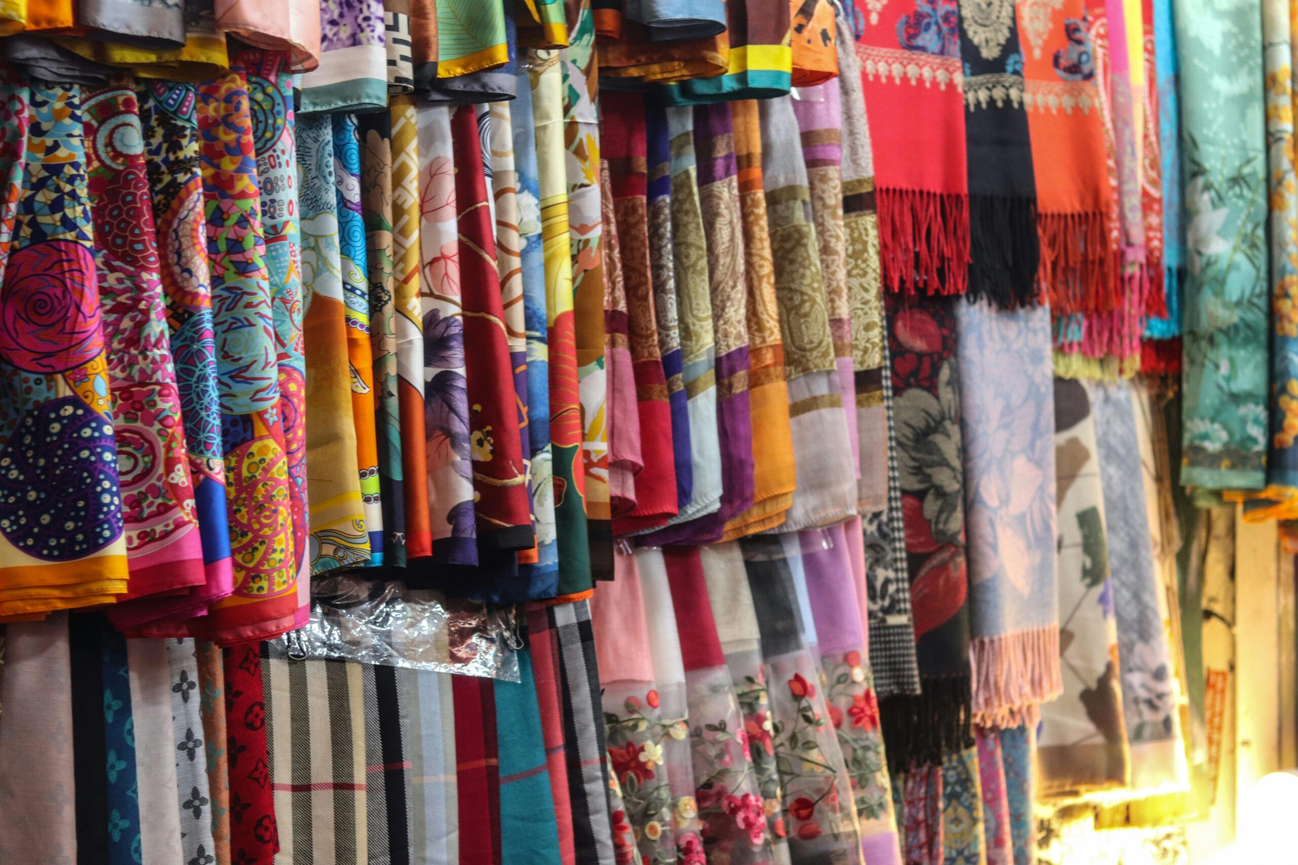 A vivid collection of silk shawls showcasing intricate patterns and bold colors on display.